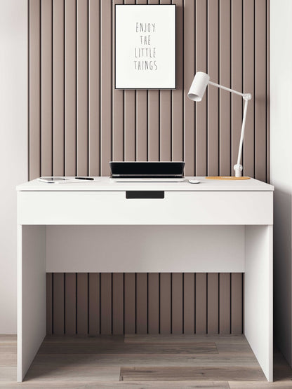 White children's desk styled in a bedroom with laptop, lamp, and wall art above