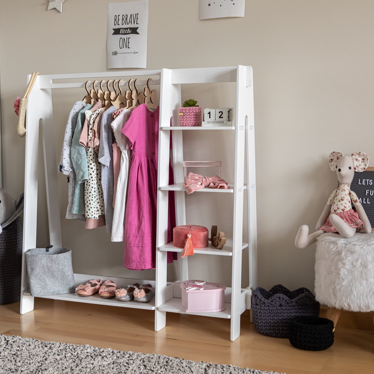 White painted kids wardrobe rack with hanging clothes, shelf storage, and pink accents
