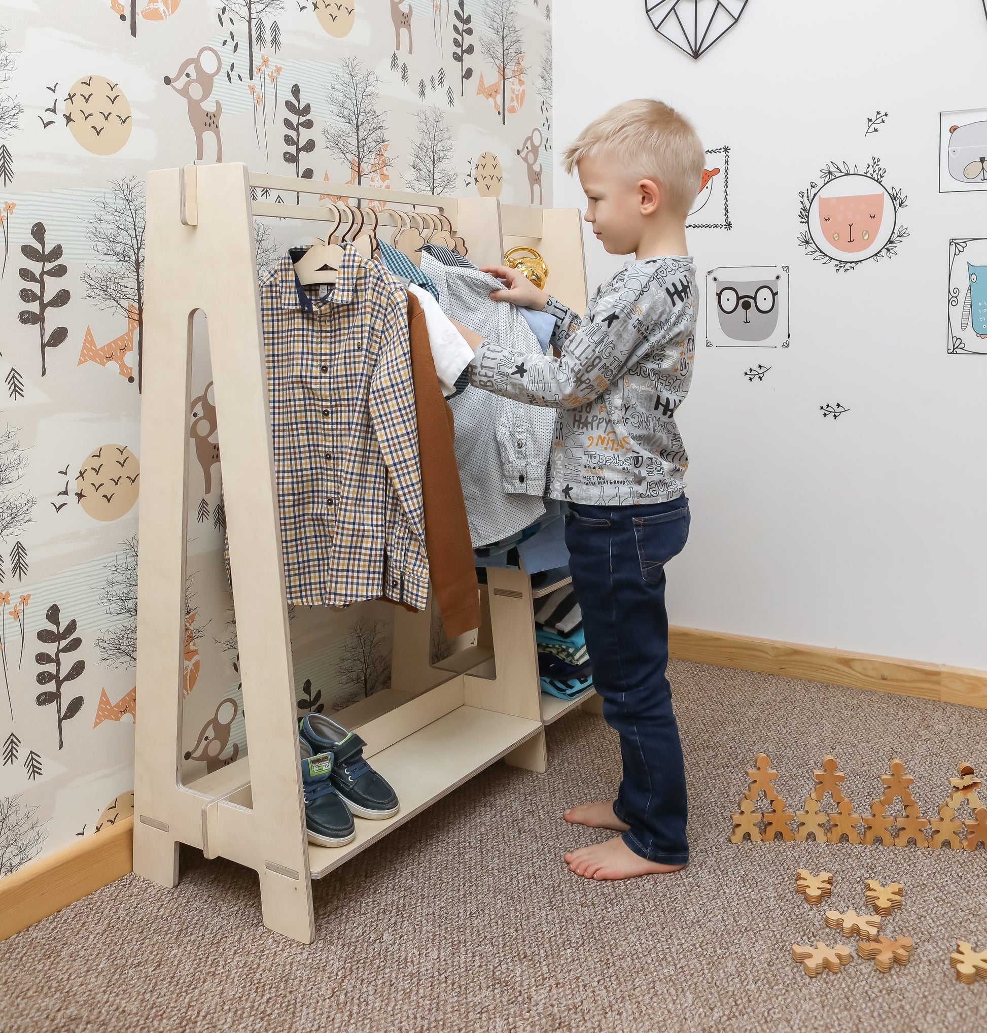 Toddler boy selecting clothes from natural wood Montessori dress-up rack with mirror