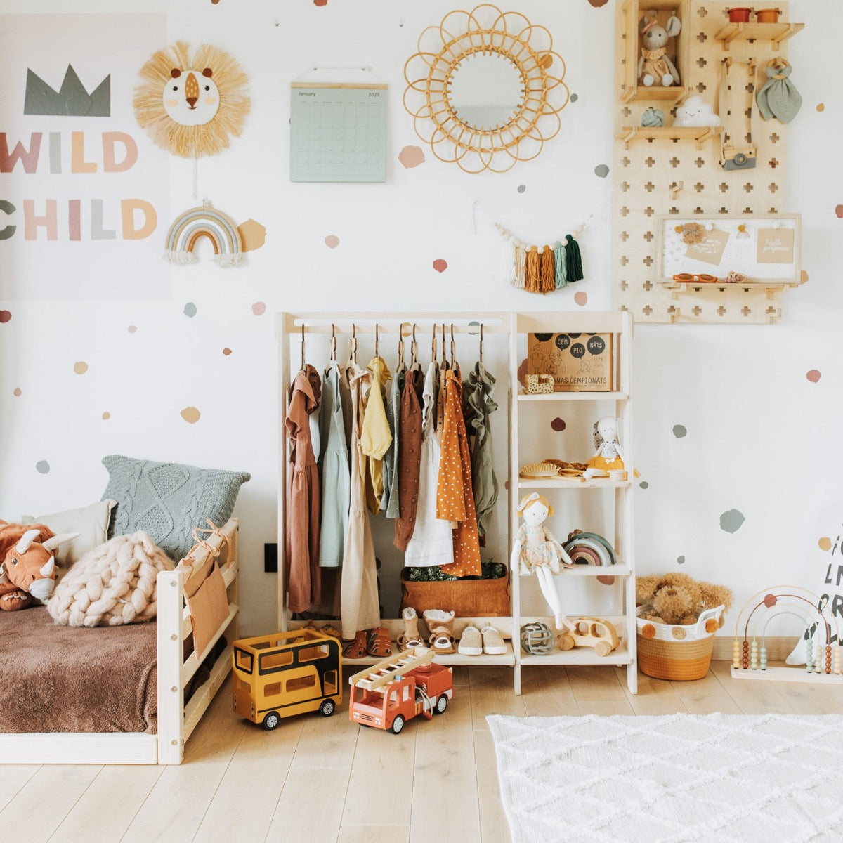 Natural wood Montessori kids clothing rack styled in playroom with wall storage and accessories