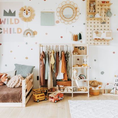 Natural wood Montessori kids clothing rack styled in playroom with wall storage and accessories