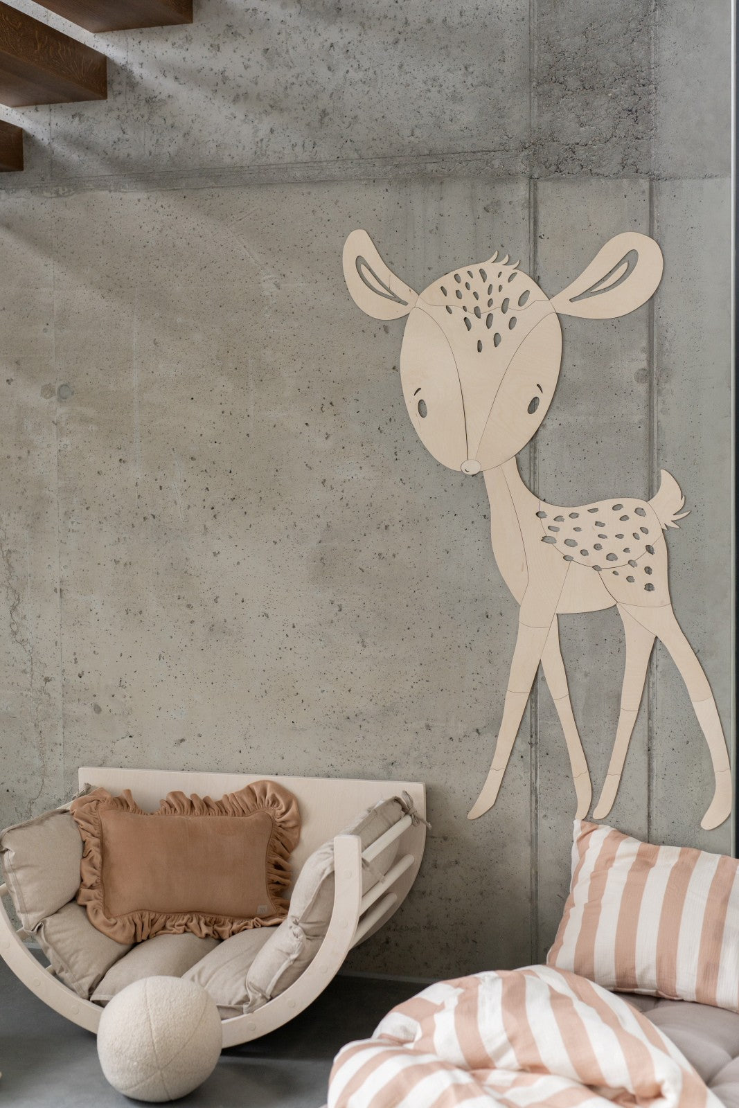Large wooden deer wall decoration in playroom above curved crib and bedding