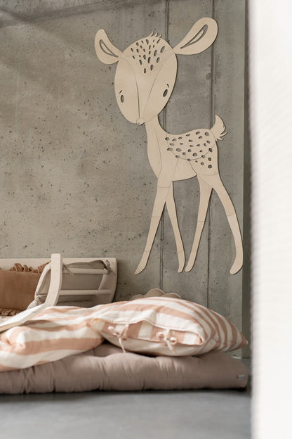 Wooden deer wall art mounted on concrete wall above pink striped bedding