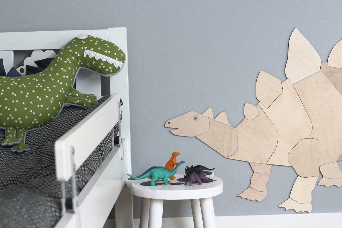 Natural plywood stegosaurus puzzle decoration displayed on grey bedroom wall