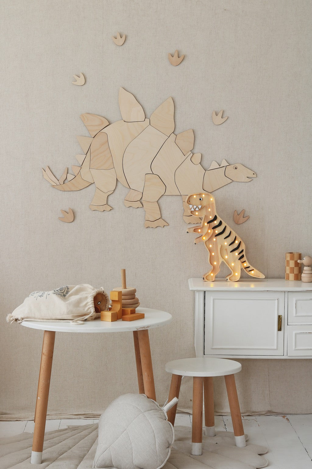 Close-up of natural wood stegosaurus wall puzzle with tan and brown dinosaur figurines