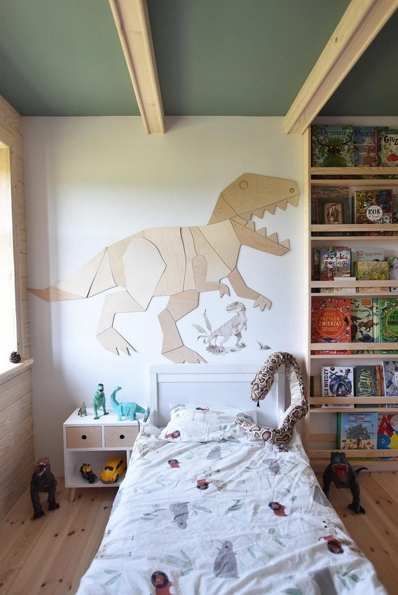 Wooden T-Rex wall decoration installed above bed in child's bedroom with toys and decor