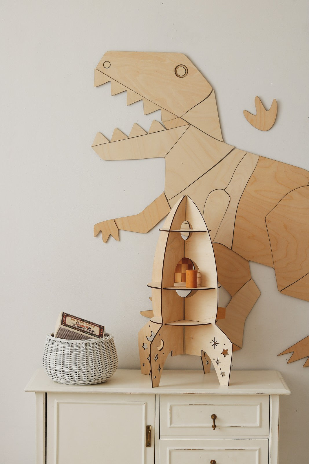 Wooden rocket ship decoration displayed next to assembled T-Rex wall art in playroom