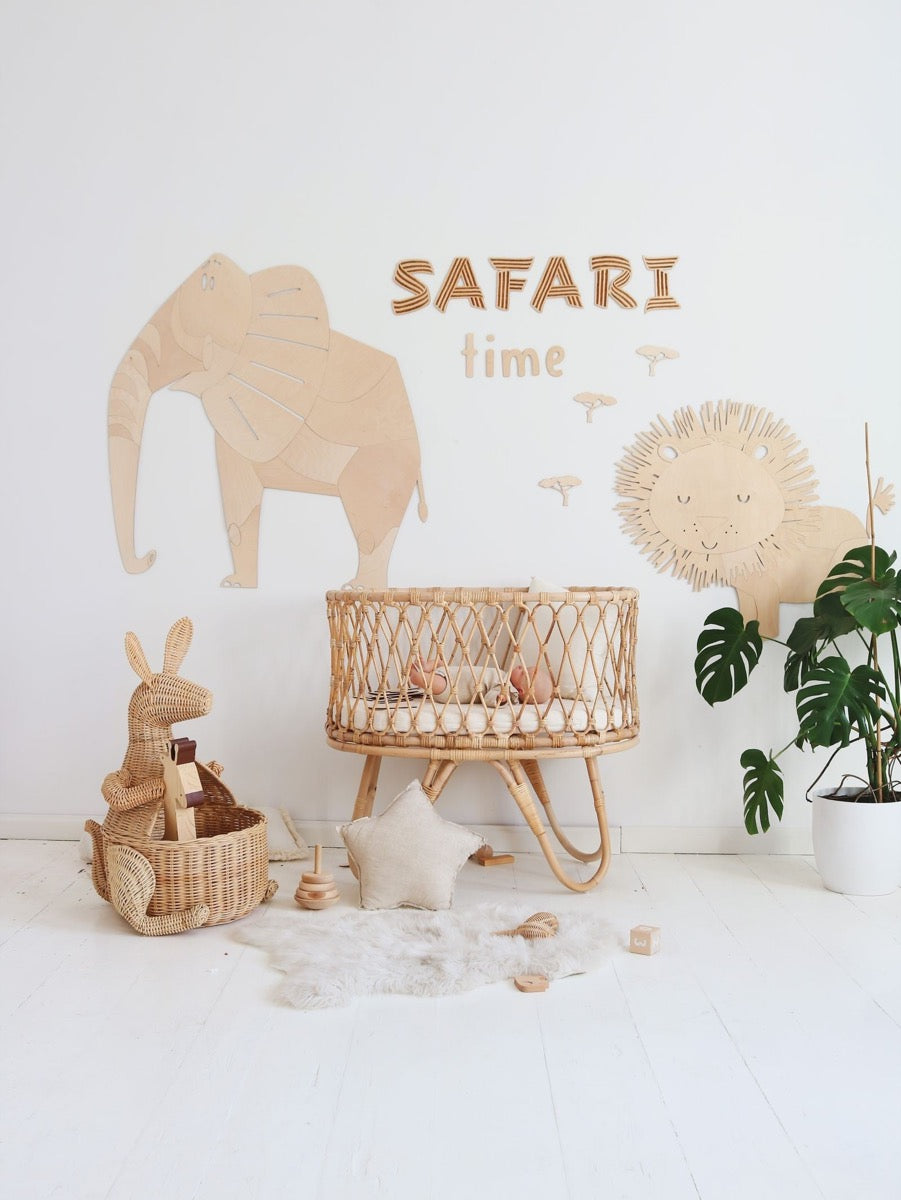 Wooden elephant and lion wall decorations in safari nursery setup with basket furniture