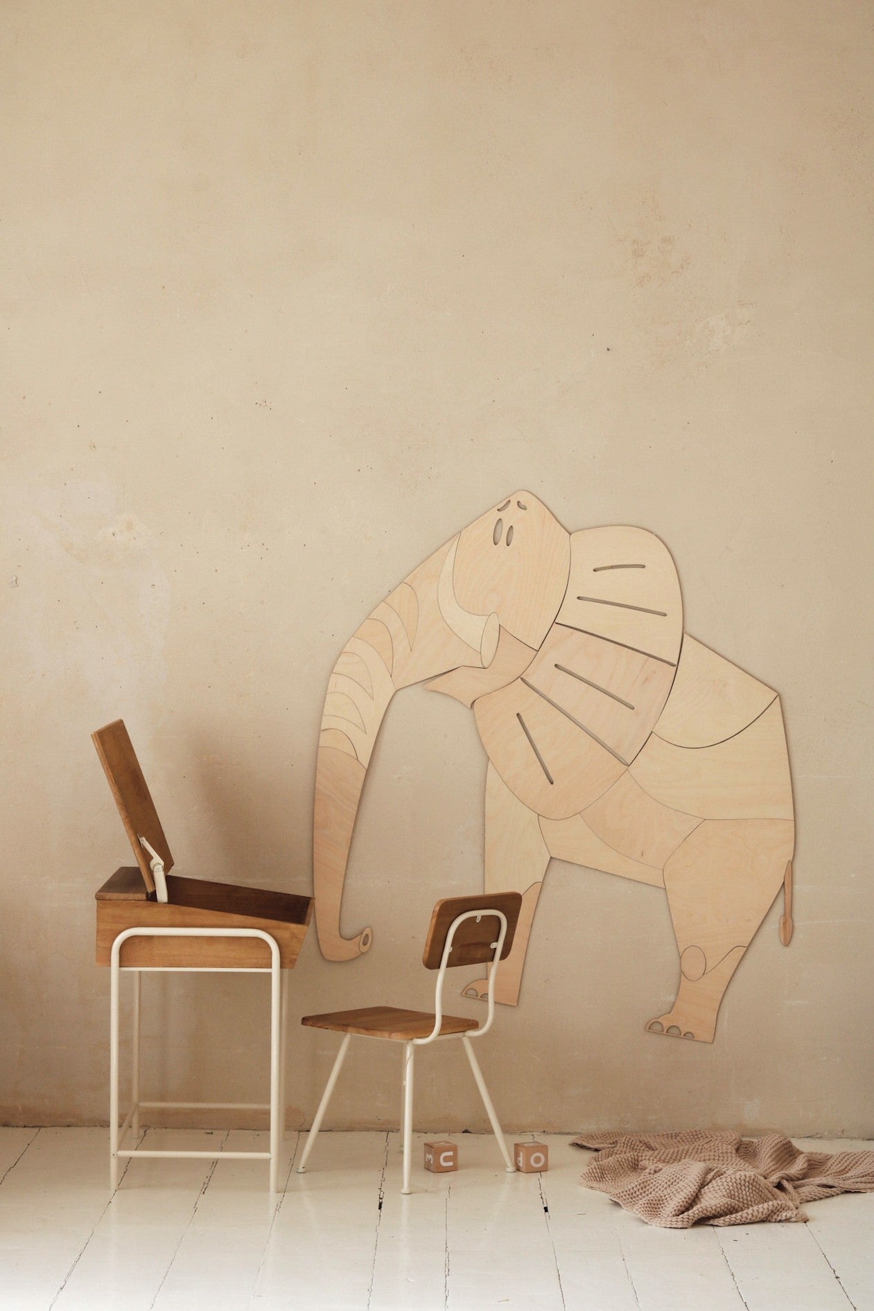 Wooden elephant wall decoration with modern furniture showing scale in playroom setting