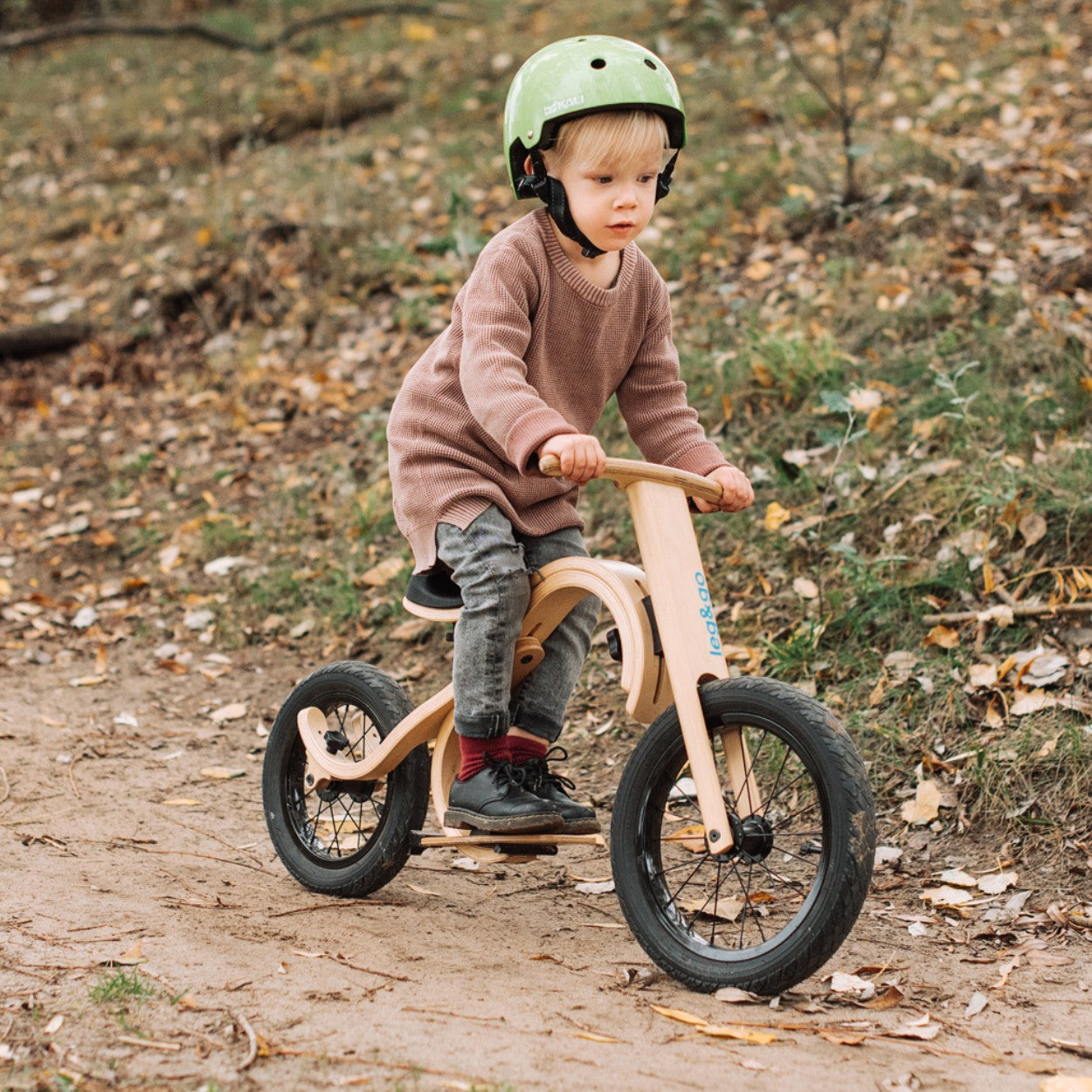 Toddler on leg&go balance bike with downhill footrest add-on on outdoor trail