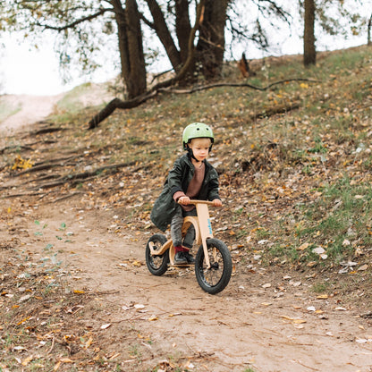 Child riding leg&go balance bike down dirt hill with footrest and brake add-on installed
