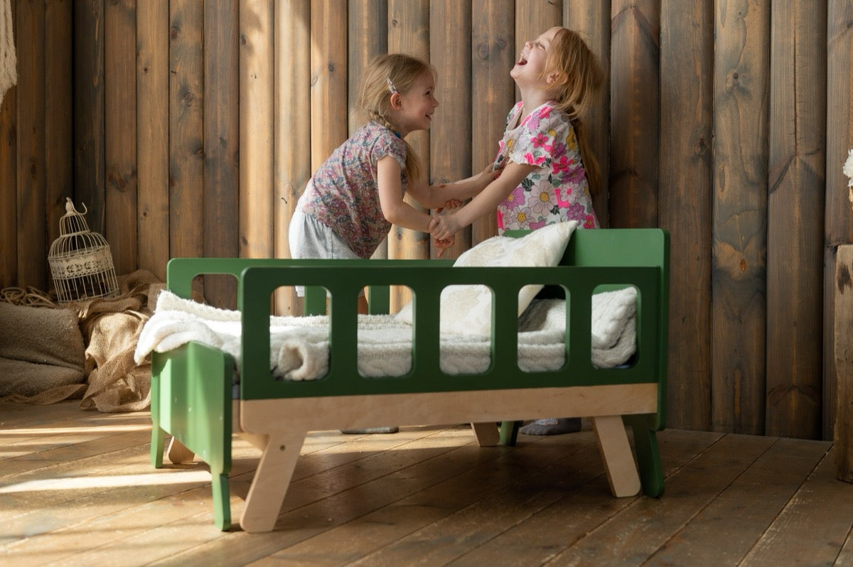Two girls laughing and playing at green Family-scl growing bed – durable toddler bed for active kids