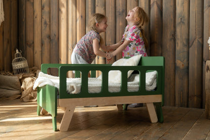 Two girls laughing and playing at green Family-scl growing bed – durable toddler bed for active kids