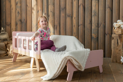 Girl sitting on extended pink Family-scl growing bed – kids adjustable bed and sofa in one piece