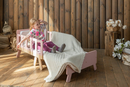Girl sitting on pink Family-scl growing bed in sofa mode – convertible kids bed and sofa in one