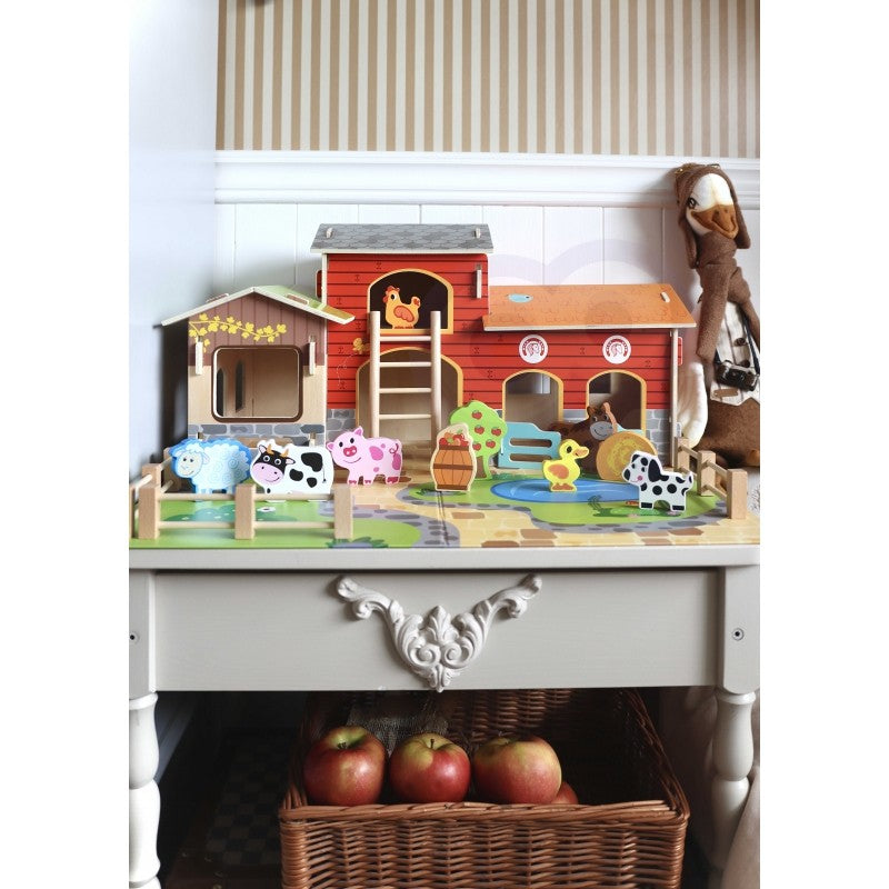 Wooden farm set displayed on white dresser with all farm buildings and animal pieces arranged together