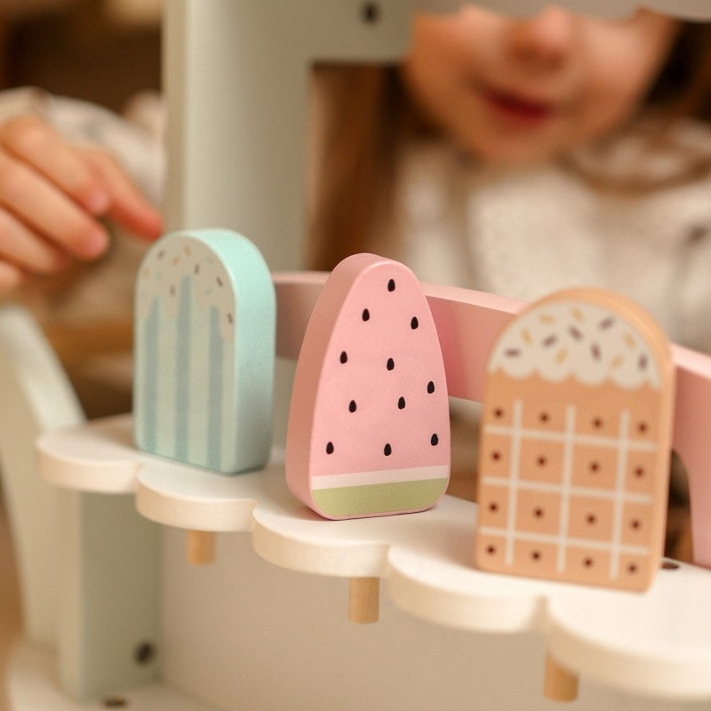 Close-up of pastel wooden ice cream scoops in mint, pink, and natural wood tones