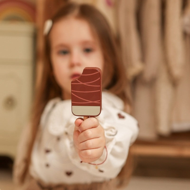 Child holding magnetic chocolate ice cream scoop with wooden stick