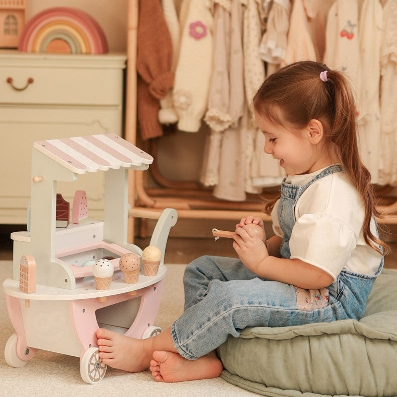 Girl playing with wooden ice cream cart while holding serving utensil