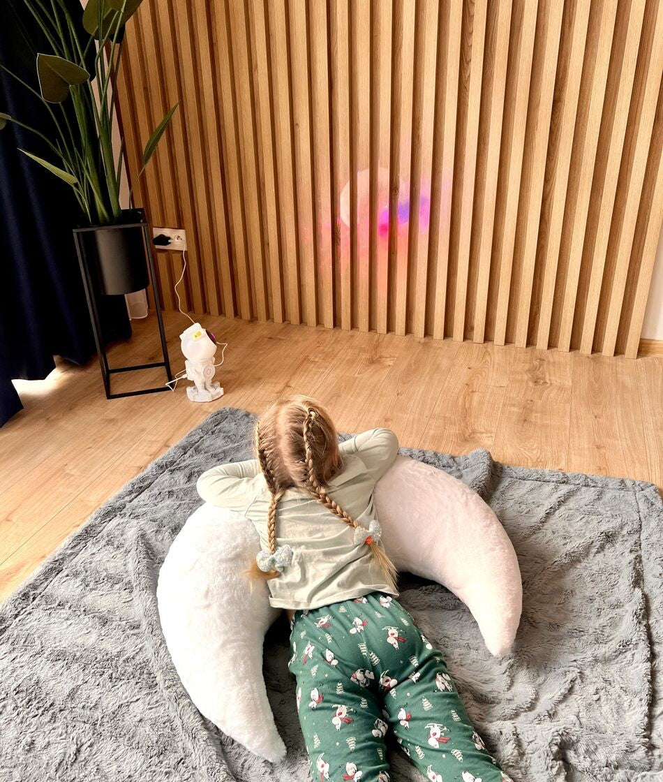 Child lying back on oversized white moon pillow, showing plush faux fur texture