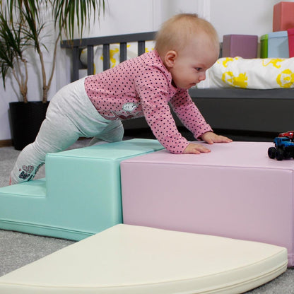 Toddler crawling over light pastel foam blocks in playroom setting