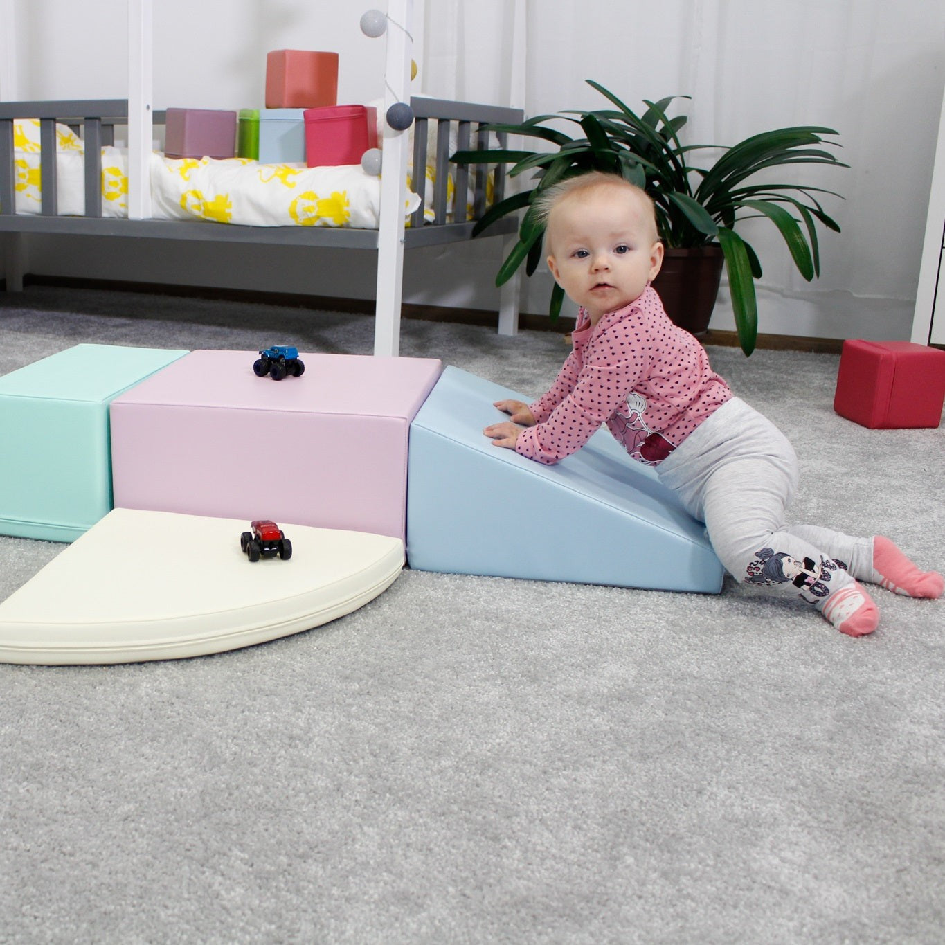 Baby sitting beside pastel foam block enjoying soft play equipment