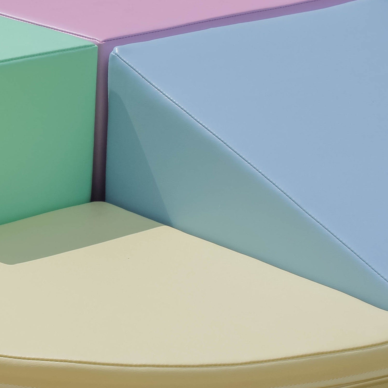 Child playing with toys on stacked light pastel foam blocks