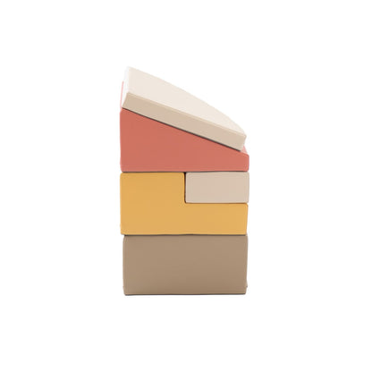 Stacked foam blocks in pastel pink, yellow, beige and gray arranged vertically