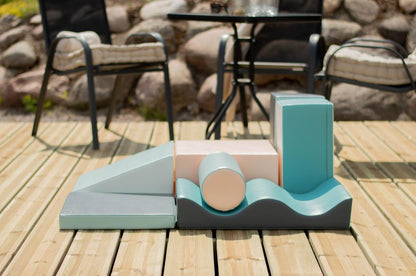Soft play foam blocks displayed on wooden deck in outdoor setting