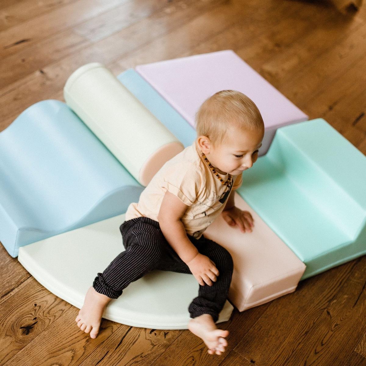 Toddler crawling over light pastel foam blocks arranged in a play structure from above