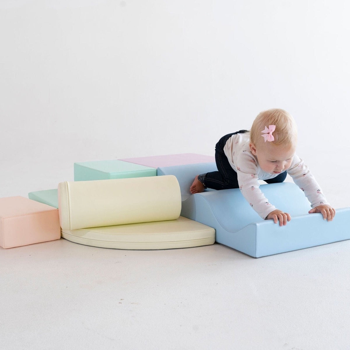 Infant crawling over light pastel foam blocks in climbing configuration