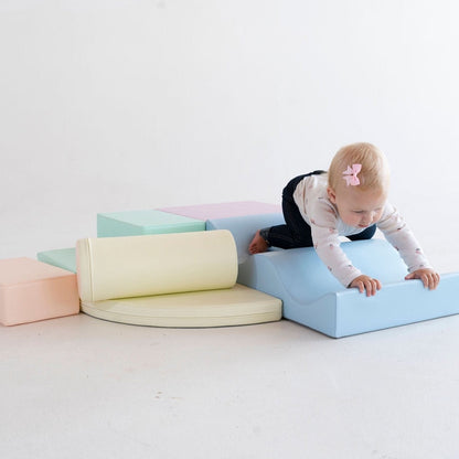 Infant crawling over light pastel foam blocks in climbing configuration