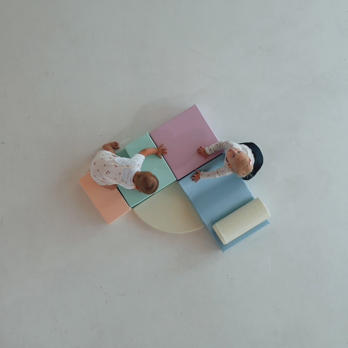 Overhead view of toddler playing with light pastel foam blocks and cylinder