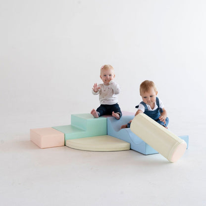 Two toddlers playing together on assembled light pastel foam block structure