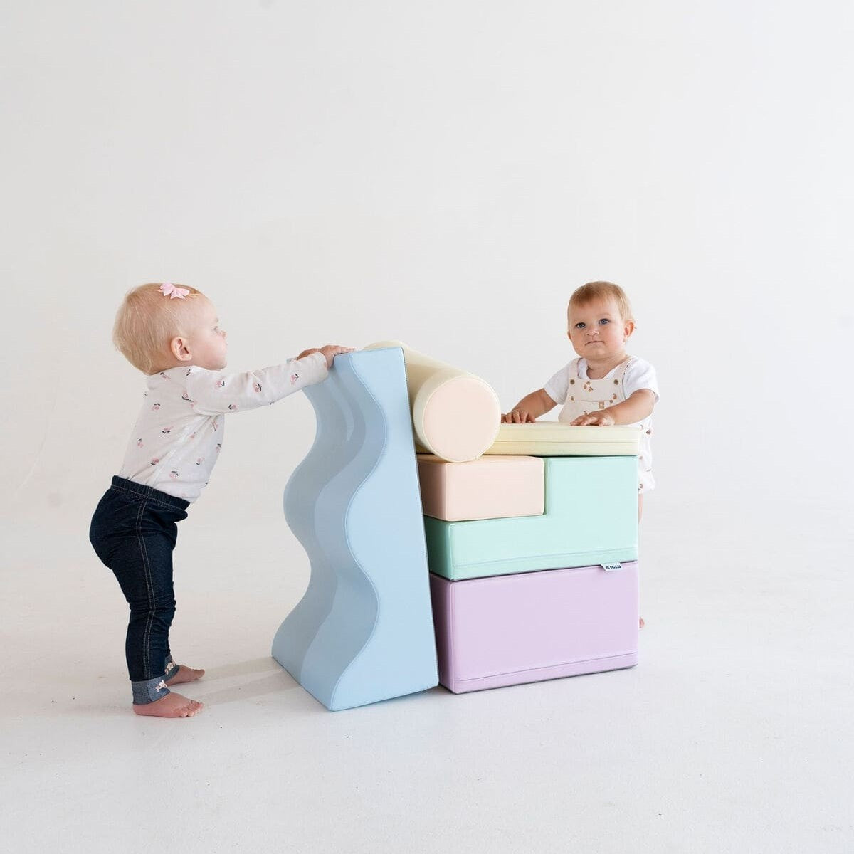 Toddler playing with light pastel foam blocks in modern playroom setting