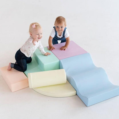 Toddler with toy playing on green foam step and assembled light pastel blocks