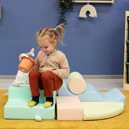Overhead view of toddler on light pastel foam block structure with cylinder