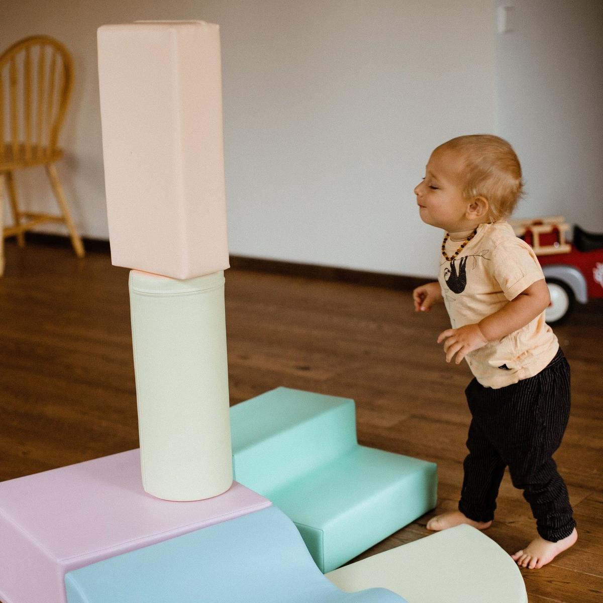 Toddler crawling on light pastel foam block structure from overhead view