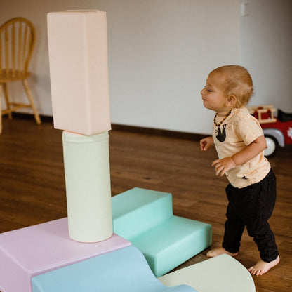 Toddler crawling on light pastel foam block structure from overhead view