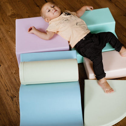 Two toddlers playing on assembled light pastel foam block structure with wavy divider