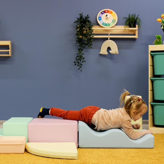 Two toddlers playing on assembled light pastel foam blocks in montessori-style setup