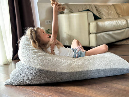 Girl relaxing on plush sherpa bean bag reading while lying down