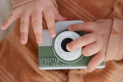Toddler's hands on the green Hoppstar Expert Laurel camera