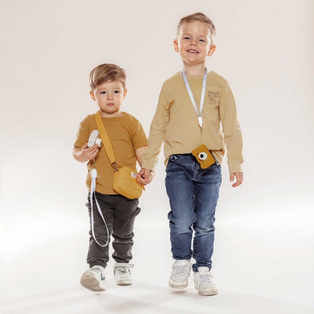 Two boys walking with the Hoppstar Expert Citron camera and a yellow bag