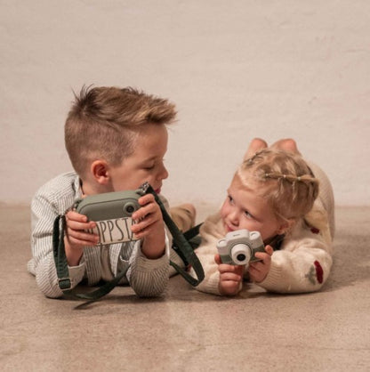 Two children lying on the floor taking photos with green Hoppstar cameras