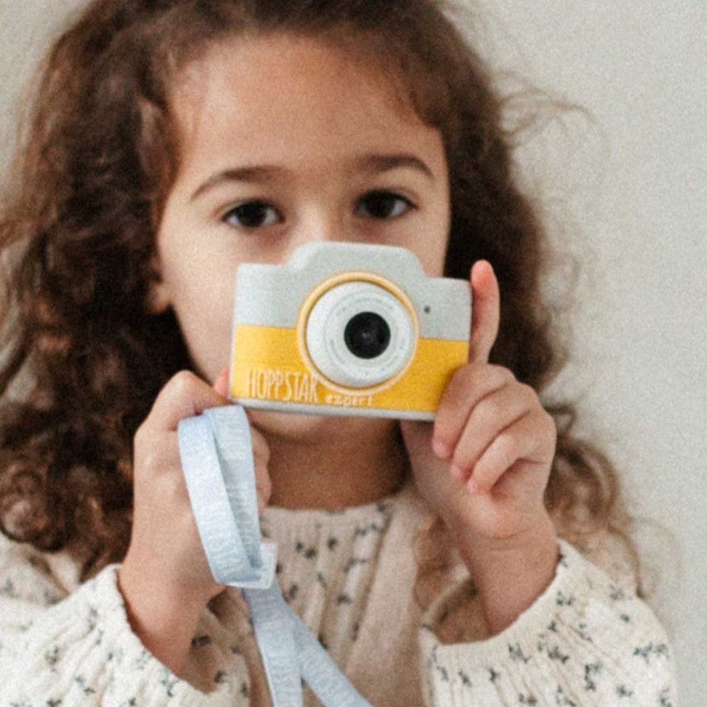 Child holding the Hoppstar Expert Citron camera with its lanyard