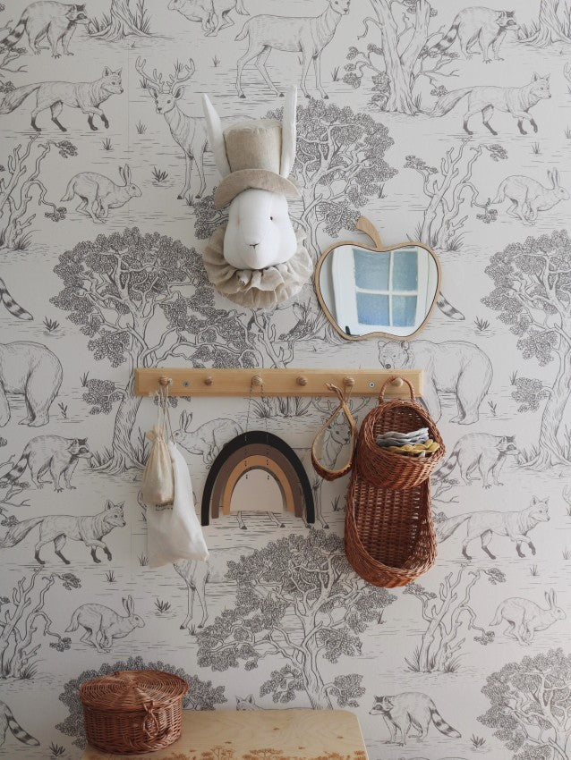 Apple-shaped acrylic mirror with wooden frame mounted on animal-print wallpaper above wooden shelf