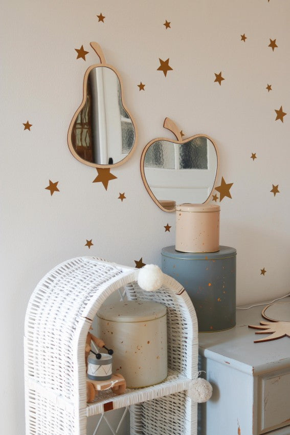 Pear and apple acrylic mirrors displayed on decorative wooden pedestals with star wall accents