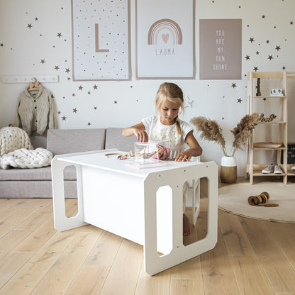 Two children using white Montessori weaning table for reading and activities