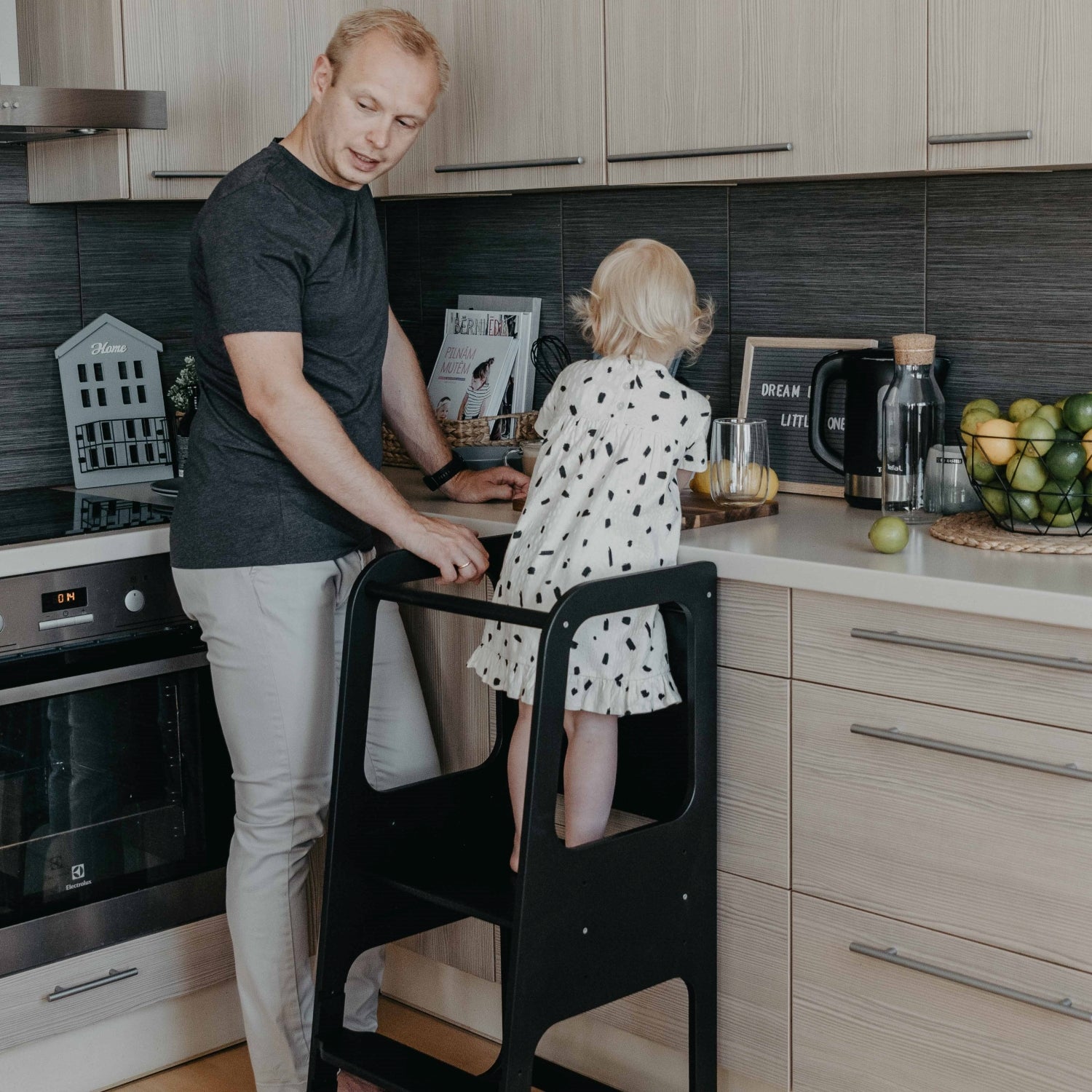 Black Montessori kitchen tower with child drawing at counter in modern kitchen